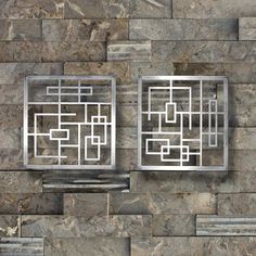 two metal squares on a stone wall next to each other in the shape of mazes