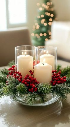 three candles are sitting in a glass bowl with holly and red berries on the rim