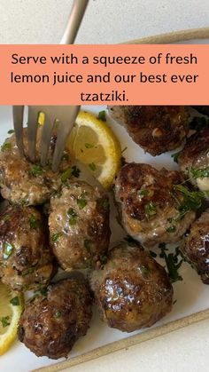 a white plate topped with meatballs and lemon wedges next to a slice of lemon