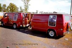 two red vans parked next to each other in a parking lot