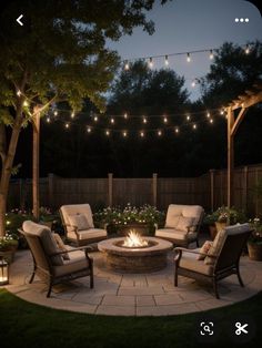 an outdoor fire pit surrounded by chairs and string lights