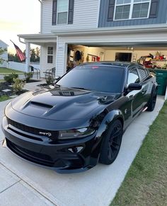 a black sports car parked in front of a house with an american flag on it