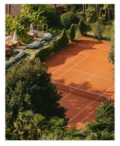 an aerial view of a tennis court surrounded by trees and shrubs, with two people on the other side