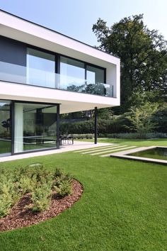 a modern house with grass and trees in the background