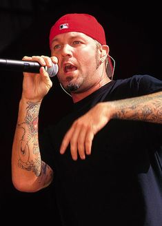 a man with tattoos on his arm holding a microphone