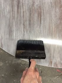 a hand holding a brush over a metal surface