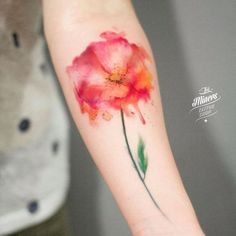 a watercolor style flower tattoo on the arm