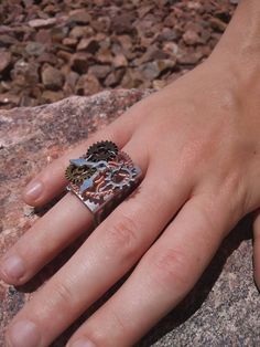 a person's hand on top of a rock with a ring in the middle