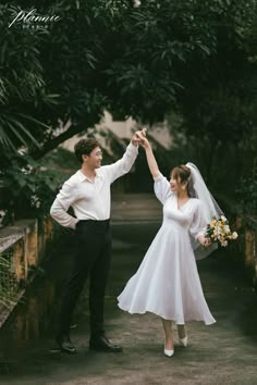 a bride and groom holding hands while standing next to each other in front of trees