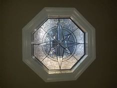 an octagonal glass window with a compass design on the top and bottom part, in a dark room