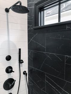 a black and white tiled shower with thermostaer, hand held shower head and handset