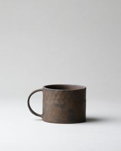 a brown coffee cup sitting on top of a white table