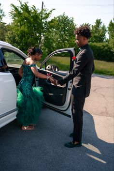 a woman in a green dress getting out of a car with her hand on the door