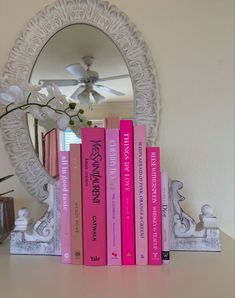 a mirror sitting on top of a white shelf filled with books