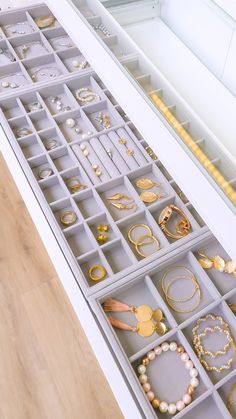 a drawer filled with lots of jewelry on top of a wooden floor