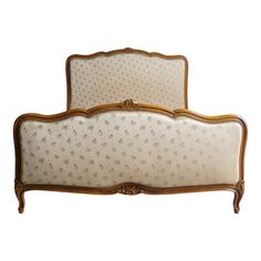 an antique style bed with gold trimmings and white upholstered headboard