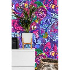 a colorful wallpaper with flowers and plants next to a white dresser in front of it