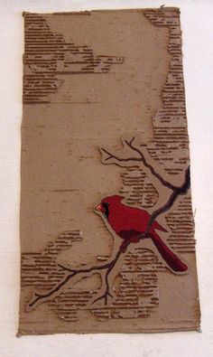 a red bird sitting on top of a tree branch next to a white wall with words written in it