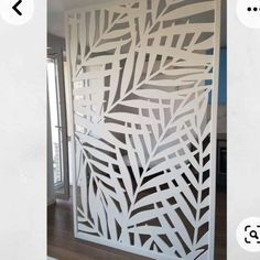 an image of a decorative screen in the shape of leaves on a white wall with wood flooring