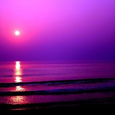 the sun is setting over the ocean with purple hues