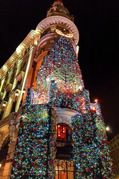 a large christmas tree is lit up in front of a building