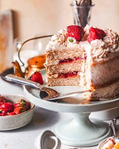 a piece of cake with strawberries is on a plate next to other desserts