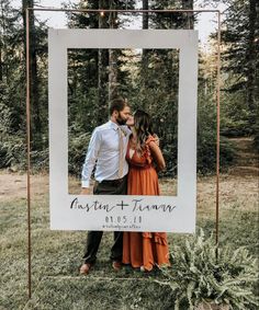 a man and woman standing next to each other in front of a white frame with the words just married on it