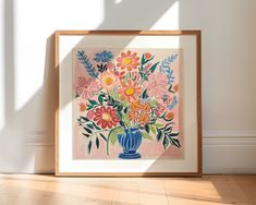 an art work with flowers in a blue vase on the floor next to a white wall