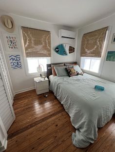 a bed room with a neatly made bed and two windows covered by shades on both sides