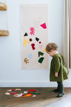 a little boy standing in front of a wall with paper cutouts on it and looking at the floor