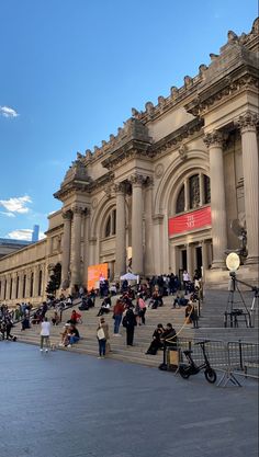 many people are sitting on the steps in front of an old building