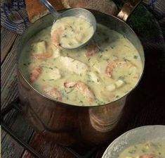 a pan filled with shrimp and cheese soup on top of a wooden table