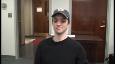 a young man wearing a hat and black shirt