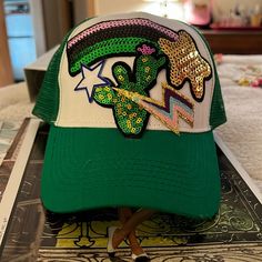 a green and white hat with sequins on it sitting on top of a bed