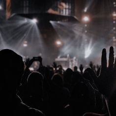 a group of people standing in front of a stage with their hands up to the sky