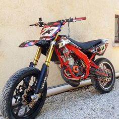 a red dirt bike parked next to a wall