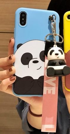 a woman holding two cell phones with panda keychains attached to the back of them