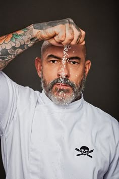 a man with tattoos on his arms and hands holding sand in front of his face