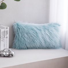 a blue furry pillow sitting on top of a white shelf next to a bookcase