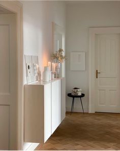 a white room with candles and vases on the shelf in front of the door