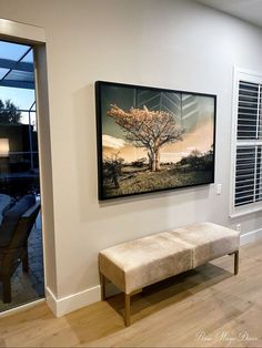 a painting hanging on the wall next to a bench in front of a sliding glass door