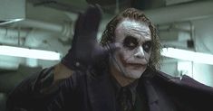 a man dressed as the joker in a dark suit with his hands up and one hand out