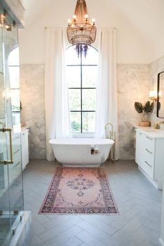 a bathroom with a chandelier hanging from the ceiling and a rug on the floor