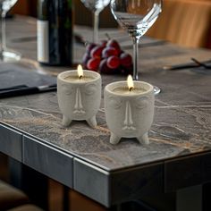 two white candles sitting on top of a table