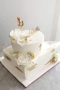 a three tiered cake with white flowers and gold decorations on it's sides