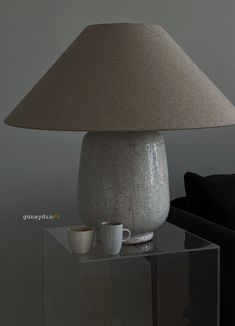 a table with a lamp and two cups on it