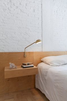 a bed sitting next to a white brick wall