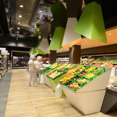 people shopping in a grocery store with fresh fruits and vegetables