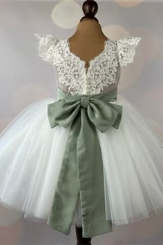 a white dress with a green bow on it