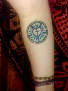 a small tattoo on the arm of a woman with a cross and heart in it